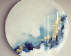 a white plate with blue and gold designs on the rim is hanging on a wall