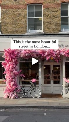 two bicycles parked in front of a building with pink flowers on the outside and a sign that says, this is the most beautiful street in london