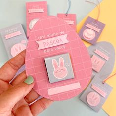 a hand holding a pink and grey pin with bunny ears on it's back