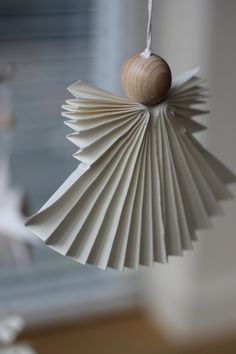 an ornament made out of folded paper with a wooden ball hanging from it