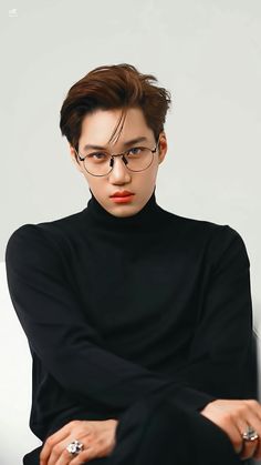 a young man with glasses sitting on a chair