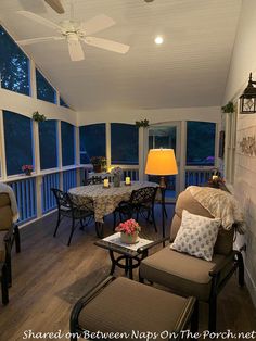 the sun shines in through large windows on this screened porch with chairs and tables