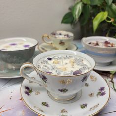 there are three cups and saucers sitting on the table with flowers in them, one is filled with cream