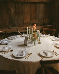 the table is set with white linens and place settings for dinner guests to enjoy