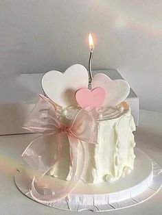 a white cake with a heart shaped candle on top