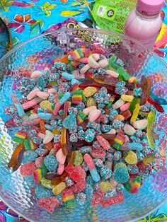 a bowl filled with lots of colorful candies on top of a blue table cloth