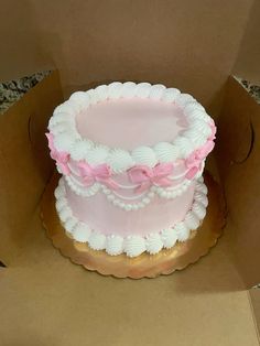 a pink and white cake sitting on top of a cardboard box