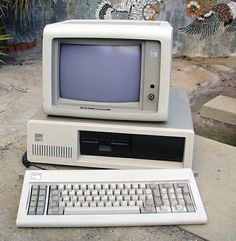 an old computer sitting on top of a concrete slab next to a keyboard and mouse