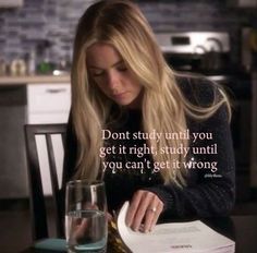 a woman sitting at a table with a book and glass in front of her reading