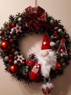 a christmas wreath with santa clause and ornaments hanging on the wall next to an ornament