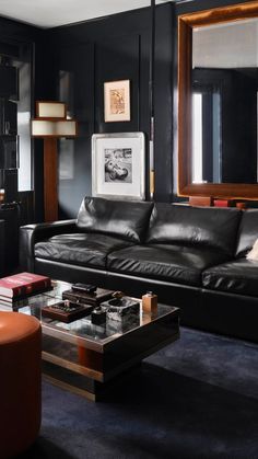 a living room with black walls and leather furniture