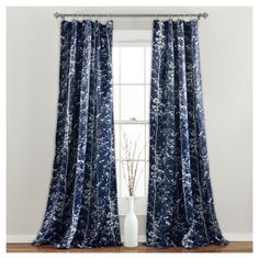 the blue and white curtain is hanging in front of a window with a vase next to it