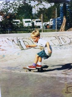 a young boy riding a skateboard on top of a cement slab with graffiti written on it