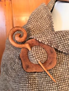 a piece of wood sitting on top of a pillow next to a wooden knitting needle