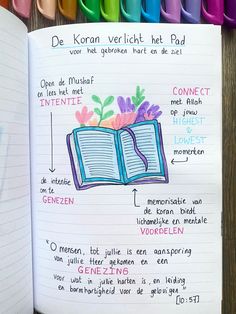 an open book with some writing on it next to colored crayons and markers