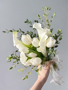 a hand holding a bouquet of white flowers