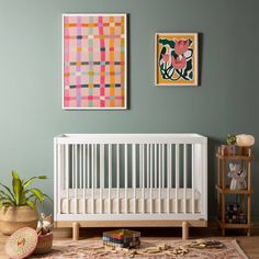 a baby's room with two paintings on the wall and a white crib