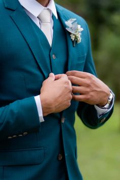 a man in a green suit adjusting his tie