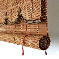 a bamboo wall hanging on the side of a white wall with red wires attached to it