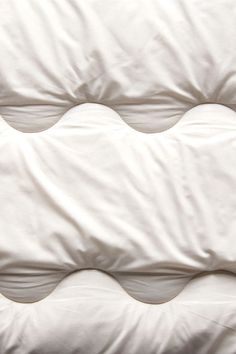 an unmade bed with white sheets and pillows