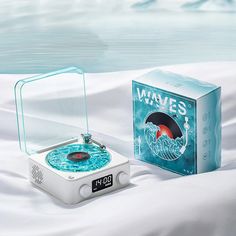 an alarm clock sitting on top of a bed next to a box that says waves