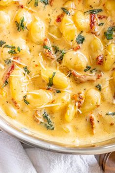 a bowl filled with pasta and spinach covered in cheese sauce on top of a white towel