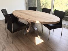 a wooden table with four black chairs around it in a living room next to a sliding glass door