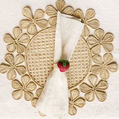 a white napkin with a strawberry on it sitting on top of a doily covered table