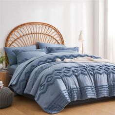 a bed with blue comforters and pillows in a room next to a wicker headboard