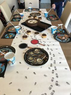 the table is set with cupcakes, plates and cups for people to eat