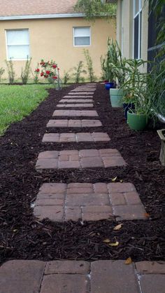 a walkway made out of bricks in front of a house