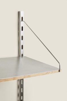 a metal shelf mounted to the side of a wall with a wooden board attached to it