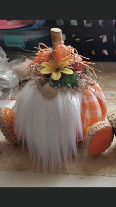 an orange and white pumpkin decorated with flowers on top of a table next to other items