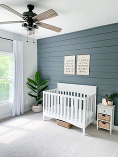 a baby's room with a white crib, dresser and ceiling fan in it