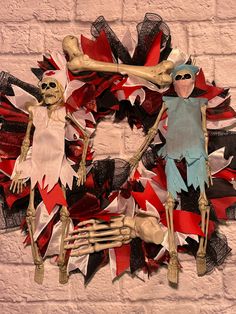 a wreath made out of fake skeletons and red, white and black ribbons on a brick wall