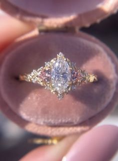 a close up of a person's hand holding an engagement ring