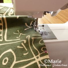 the sewing machine is on top of the green and white tablecloth that has been sewn