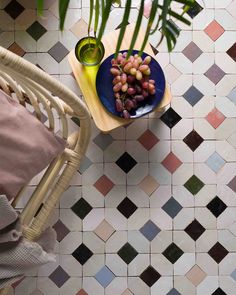 a table topped with a plate of fruit next to a potted plant on top of a tiled floor