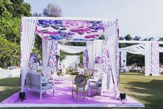 an outdoor wedding setup with white drapes and purple flowers