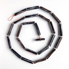 a group of black and orange necklaces on a white surface with wires attached to them