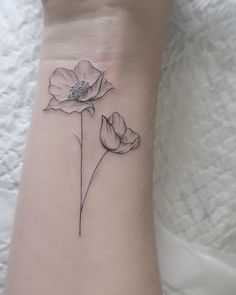 a small wrist tattoo with two flowers on the left side of the arm and one flower in the middle