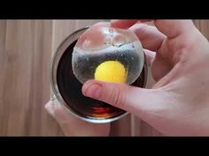 someone is holding an egg in a glass with water and oil on the inside,