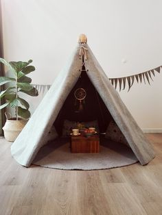 a teepee tent sitting on top of a wooden floor next to a potted plant