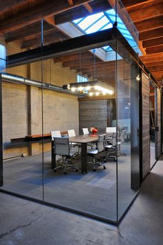 an office with glass walls and tables in the center, surrounded by concrete flooring