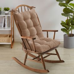 a wooden rocking chair in front of a potted plant