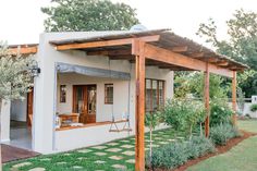 a small house with a covered patio and green grass on the ground in front of it