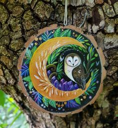 an ornament hanging on a tree in the shape of a sleeping owl with green leaves