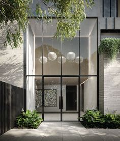 the entrance to an apartment building with glass walls and plants growing on it's sides