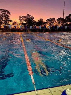 people are swimming in the pool at sunset