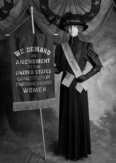 a woman standing next to a sign that says we demand for the american government and women